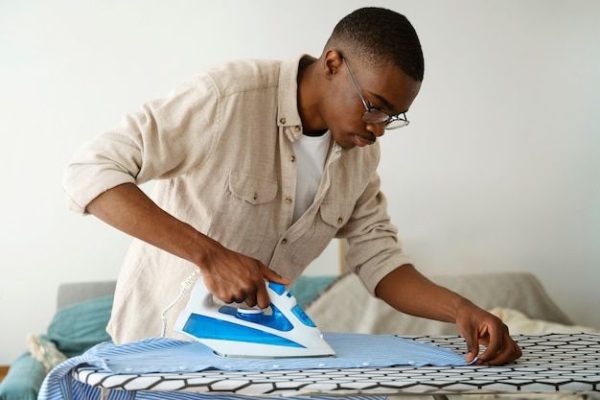 medium shot man servant ironing shirt free photo